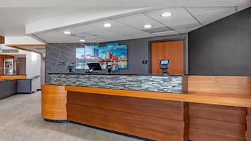 A reception desk with a digital display, a phone, and a 'Stay Happy' sign.