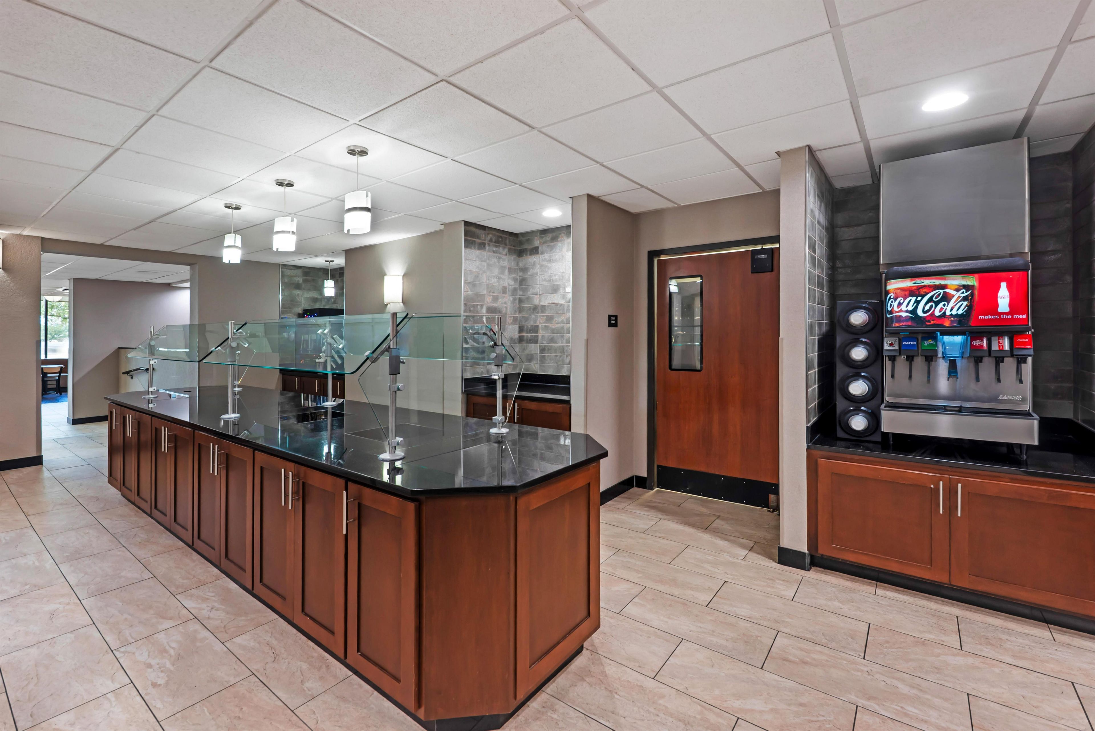 Una cocina moderna con una isla central, un refrigerador Coca-Cola empotrado y una barandilla de vidrio.