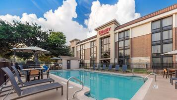 A Drury Inn & Suites with a swimming pool, outdoor seating, and a clear sky.