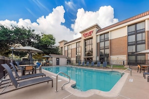 A Drury Inn & Suites with a swimming pool, outdoor seating, and a clear sky. - Drury Inn & Suites Austin North (Austin)