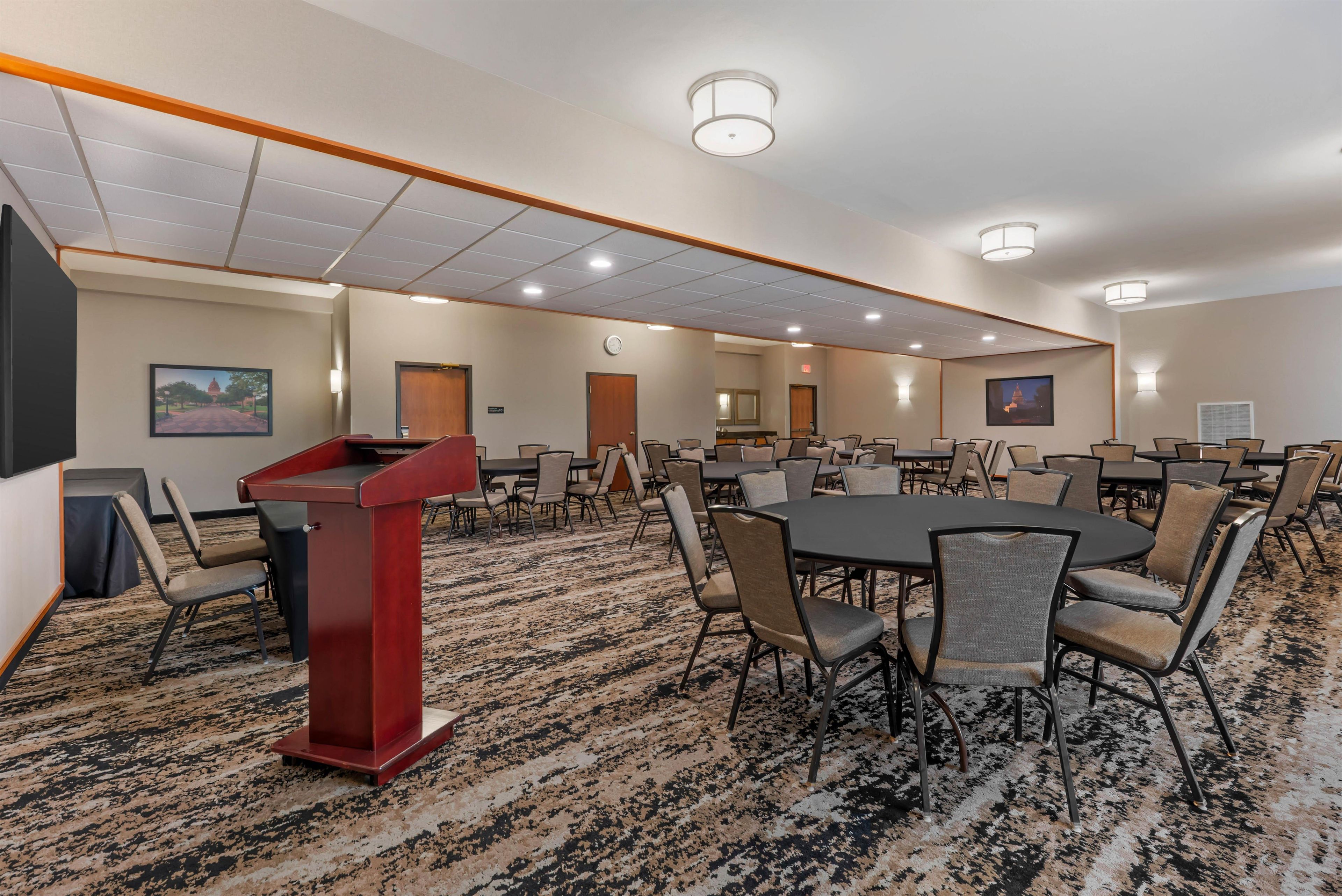 A conference room with a podium, multiple tables, and chairs.