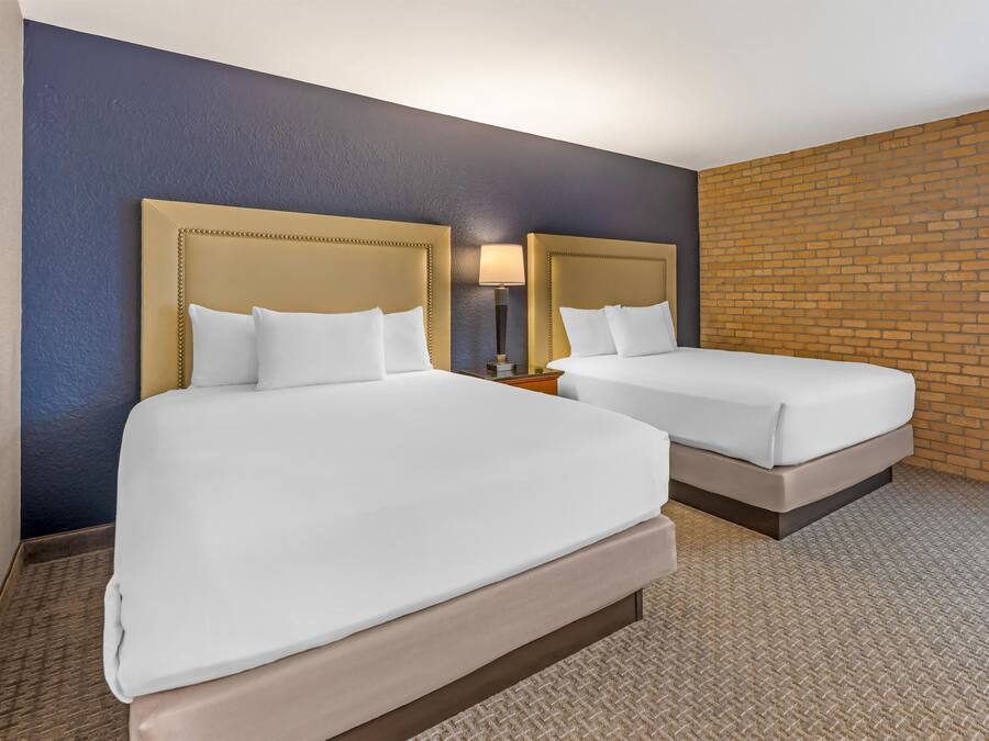 Ein Hotelzimmer mit zwei Betten, einer Backsteinwand und einer blauen Wand.