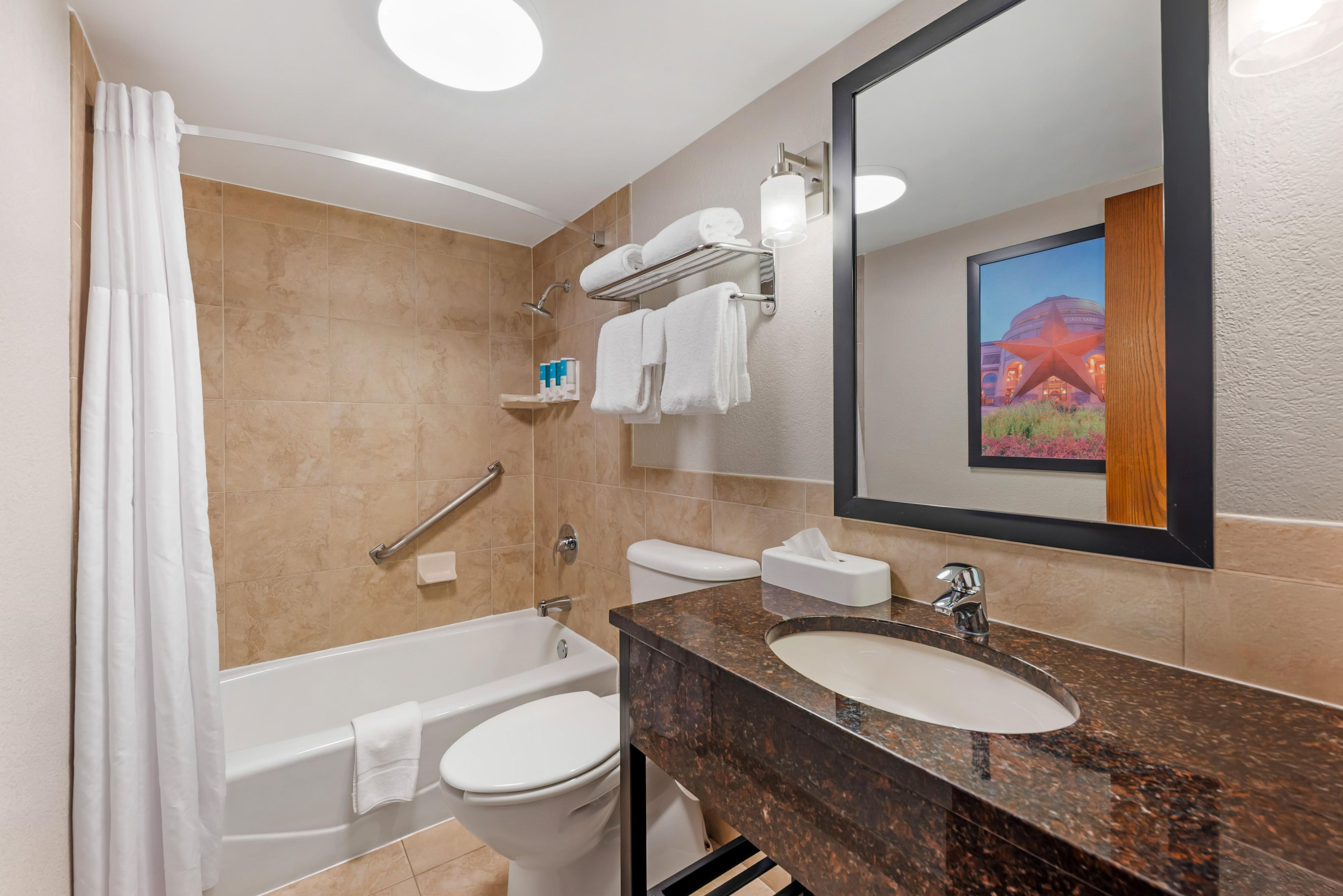 A modern bathroom with a bathtub, toilet, sink, and a large mirror.