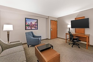 A hotel room with a sofa, armchair, desk, television, and a painting on the wall. - Drury Inn & Suites Austin North (Austin)