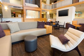 A modern lounge area with a sofa, armchairs, and a small table. - Drury Inn & Suites Austin North (Austin)