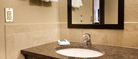 A bathroom with a granite countertop sink, a mirror, and two towel racks.