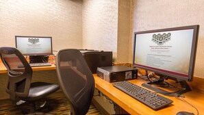 A hotel room with two desktop computers, a keyboard, a mouse, and a chair. - Drury Inn & Suites Austin North (Austin)