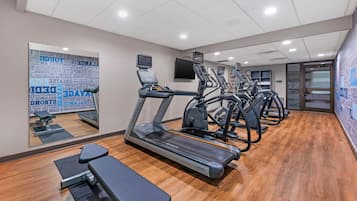 Un gimnasio con cintas de correr, una banca y un espejo con mensajes motivacionales.