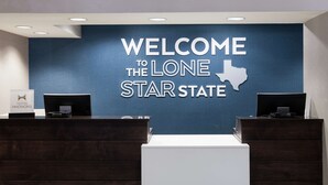 A reception desk with a blue wall displaying "WELCOME TO THE LONE STAR STATE" and a Hilton Honors sign. - Hampton Inn Austin NW near The Domain (Austin)
