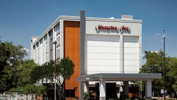 A Hampton Inn hotel with a modern facade, a welcoming entrance, and a flagpole.