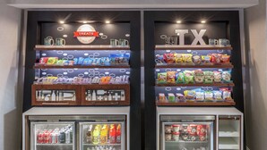 A snack display with various packaged goods and a refrigerated section with beverages. - Hampton Inn Austin NW near The Domain (Austin)