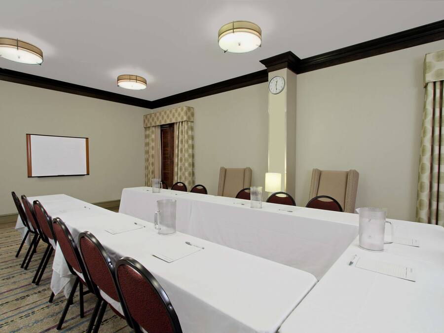 A conference room with a long table, chairs, a clock, and a projector screen.