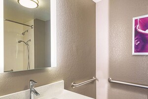 A bathroom with a sink, mirror, and handrails.