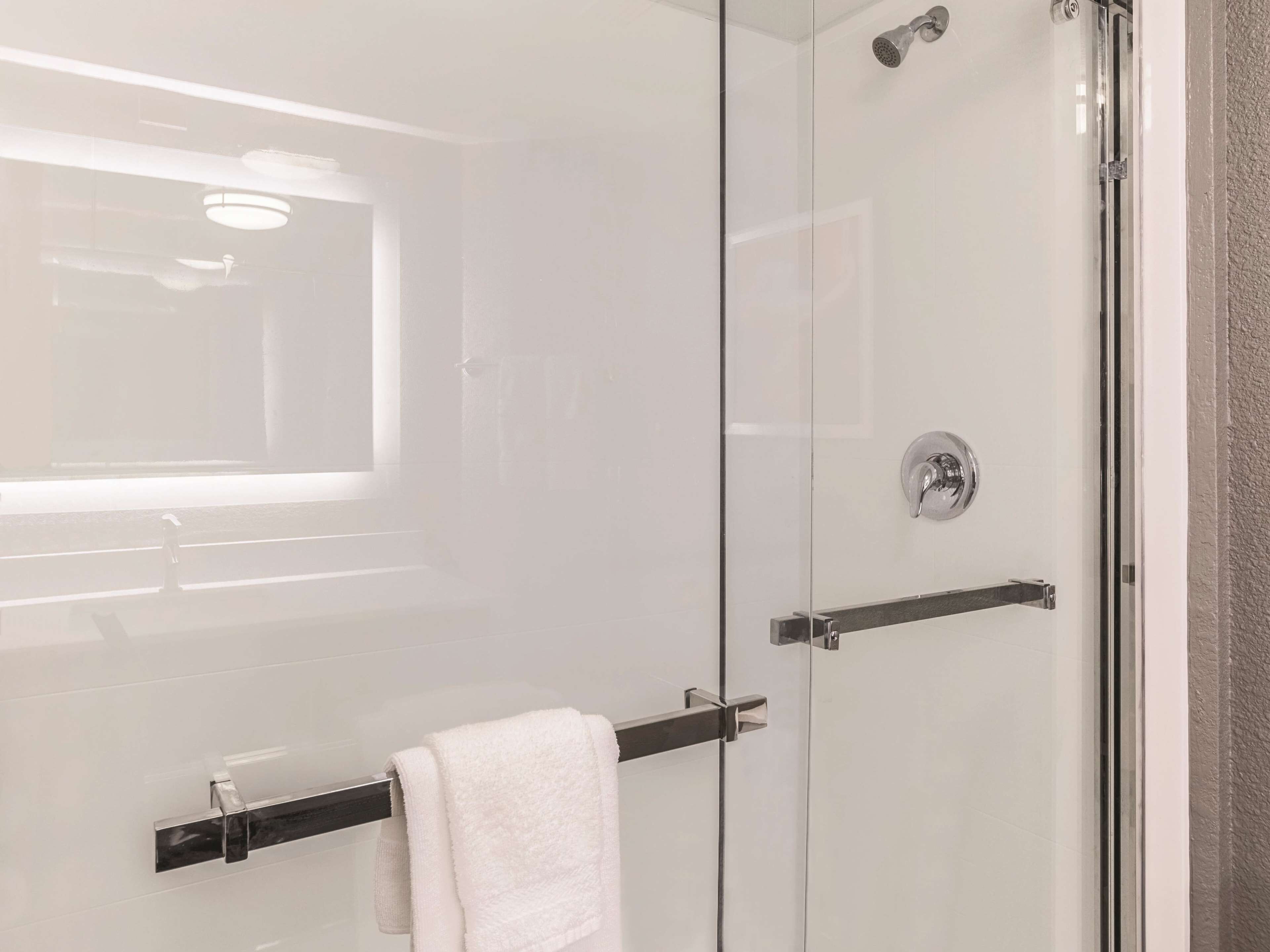 A modern bathroom with a glass shower enclosure, a towel rack, and a window providing natural light.