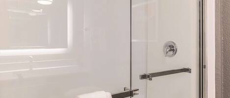 A modern bathroom with a glass shower enclosure, a towel rack, and a window providing natural light.