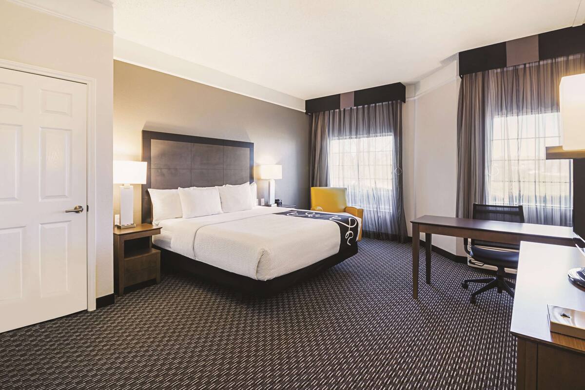 Una habitación de hotel con cama, mesitas de noche, escritorio y silla.