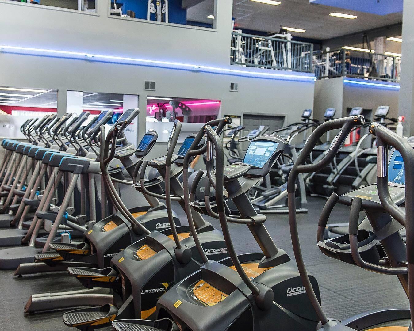 Un gimnasio con varias cintas de correr alineadas.