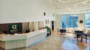 A hotel reception area with a modern design, featuring a reception desk, seating area, and large windows providing natural light. - Quality Inn & Suites Gatineau (Gatineau)
