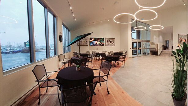 A spacious conference room with large windows, modern lighting, and a view of a parking lot. - Quality Inn & Suites Gatineau (Gatineau)