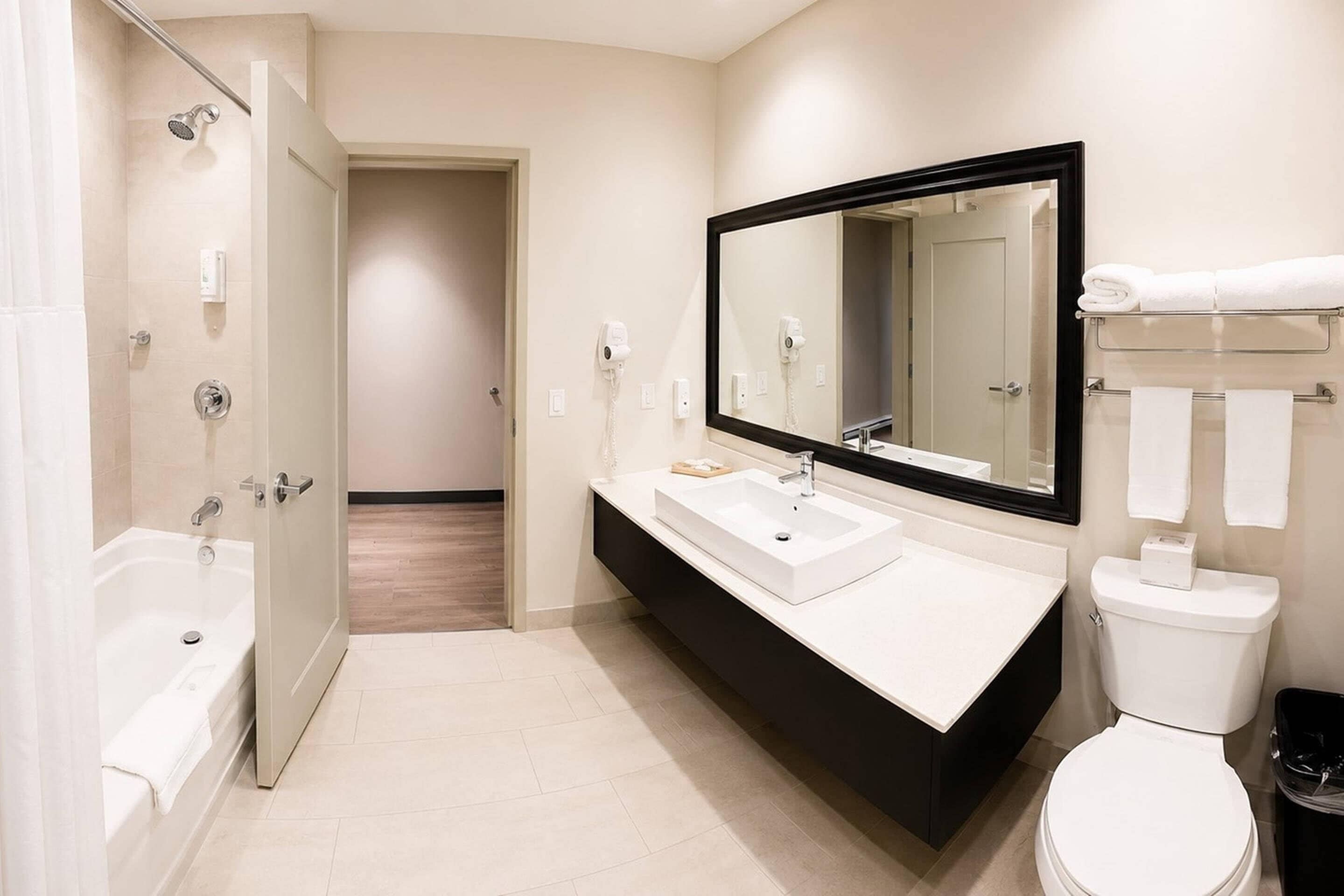 A modern bathroom with a bathtub, sink, mirror, and toilet.