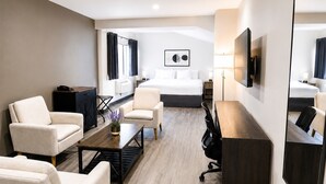 A hotel room with a bed, two armchairs, a desk, a TV, and a window. - Quality Inn & Suites Gatineau (Gatineau)