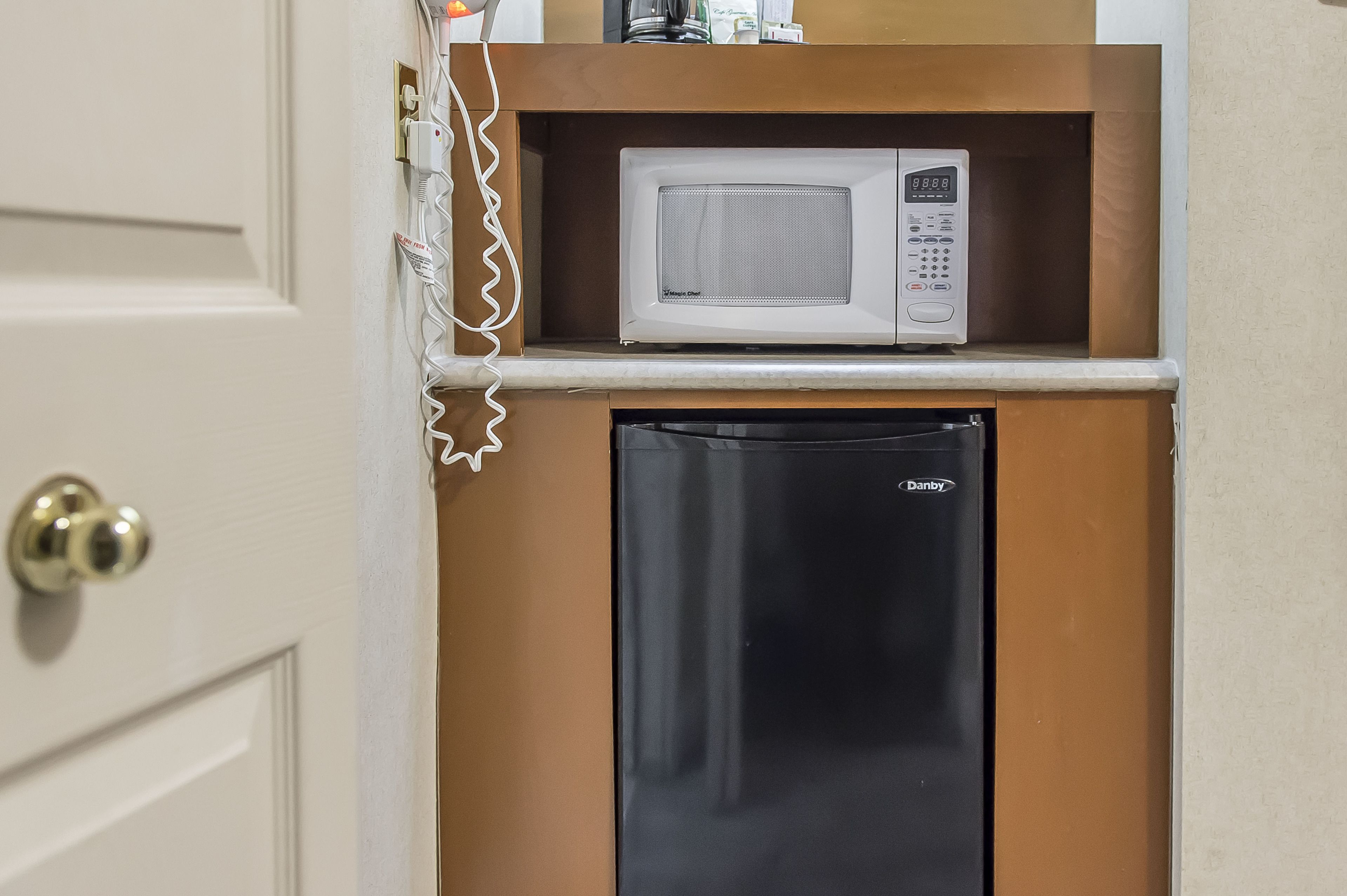 A compact kitchen with a microwave and a black Danby refrigerator.