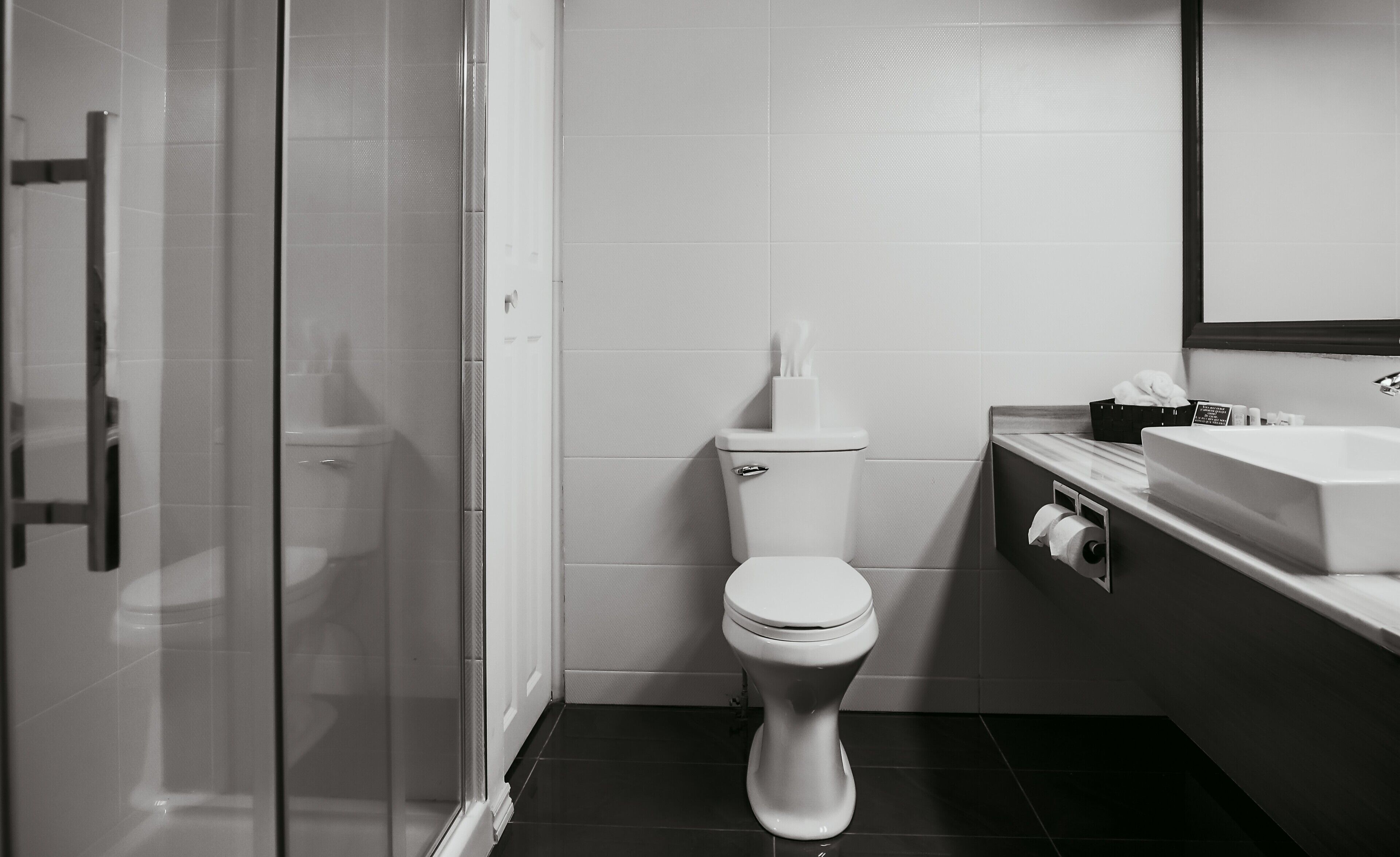 Un baño moderno con inodoro, cabina de ducha de vidrio y lavabo con espejo.