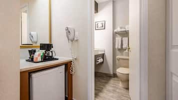 A hotel bathroom with a sink, mirror, hairdryer, and towel rack.