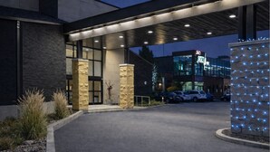 A hotel entrance with a modern design, featuring stone pillars, a covered walkway, and a parking area. - Quality Inn & Suites Gatineau (Gatineau)
