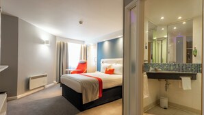 A hotel room with a bed, a bathroom with a sink and mirror, and a window with curtains. - Holiday Inn Express Glasgow City Theatreland by IHG (Glasgow)