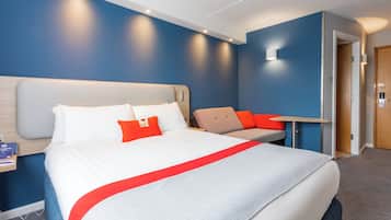 Una habitación de hotel con una cama grande, un escritorio y una silla.