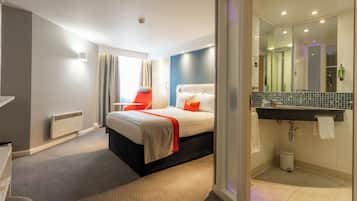 Habitación de hotel moderna con cama, escritorio y baño.