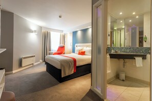 Habitación de hotel moderna con cama, escritorio y baño.
