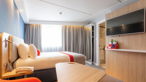 A modern hotel room with a bed, a desk, a chair, a TV, and a wardrobe. - Holiday Inn Express Glasgow City Theatreland by IHG (Glasgow)