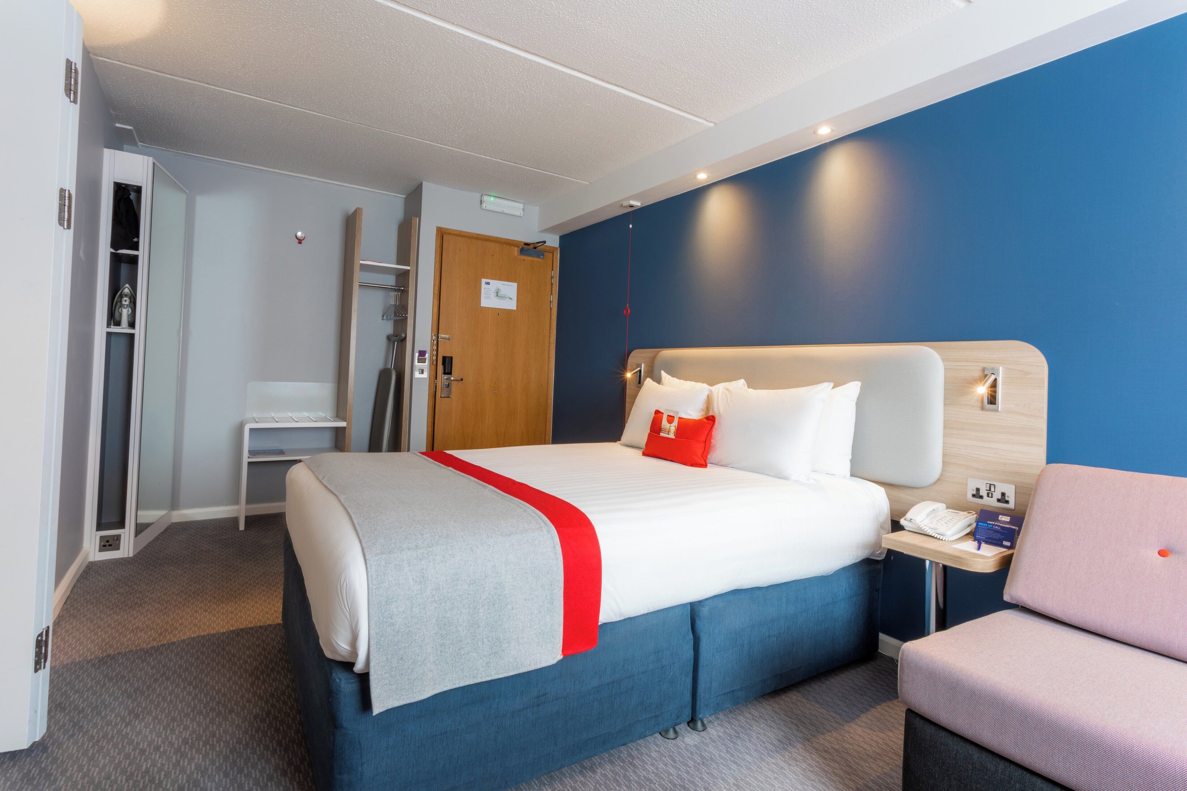 Een hotelkamer met een bed, nachtkastje en een stoel.