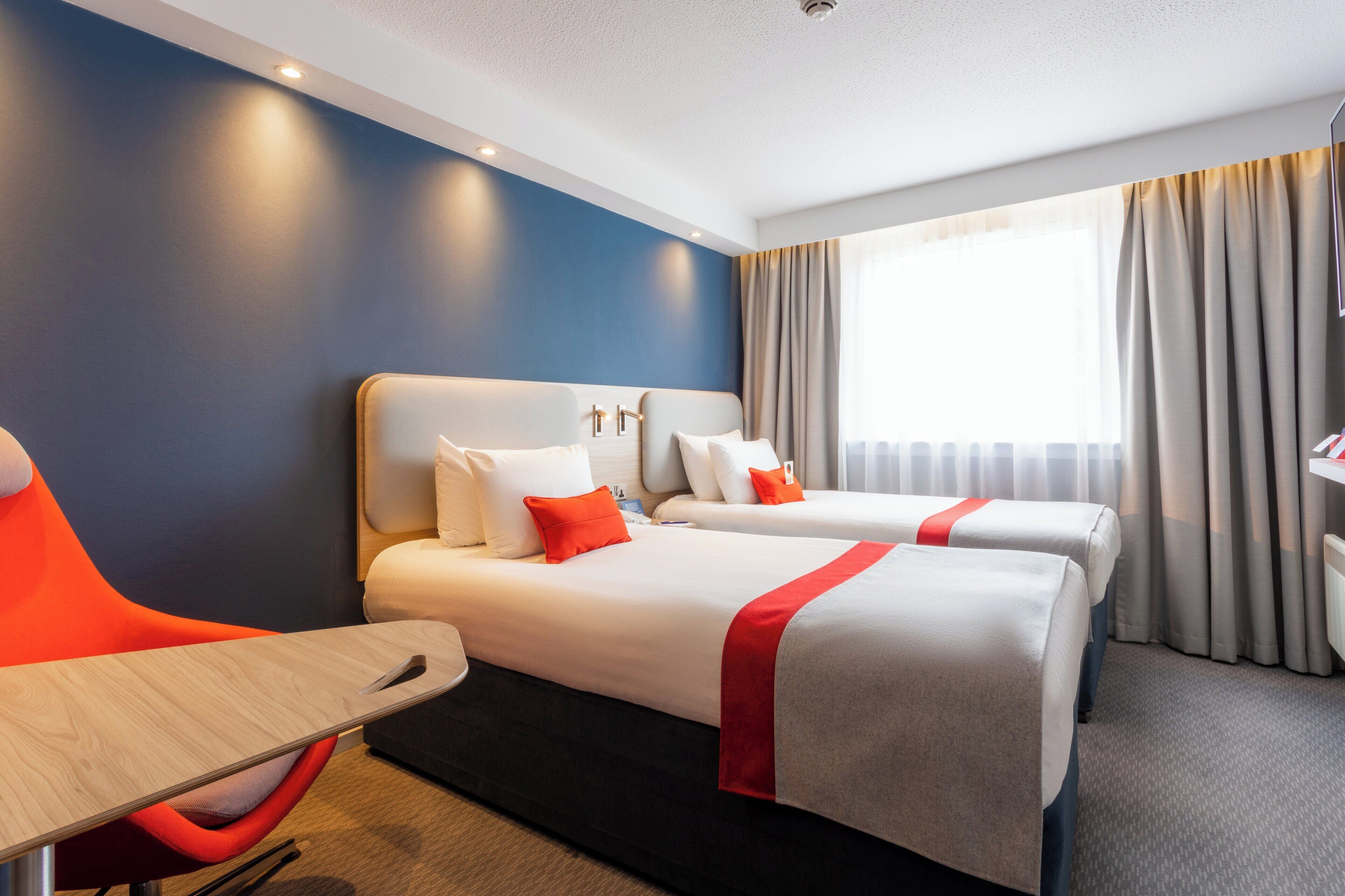 Een hotelkamer met twee bedden, een bureau en een stoel.