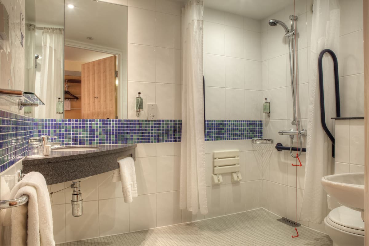 A modern bathroom with a shower, toilet, and sink.
