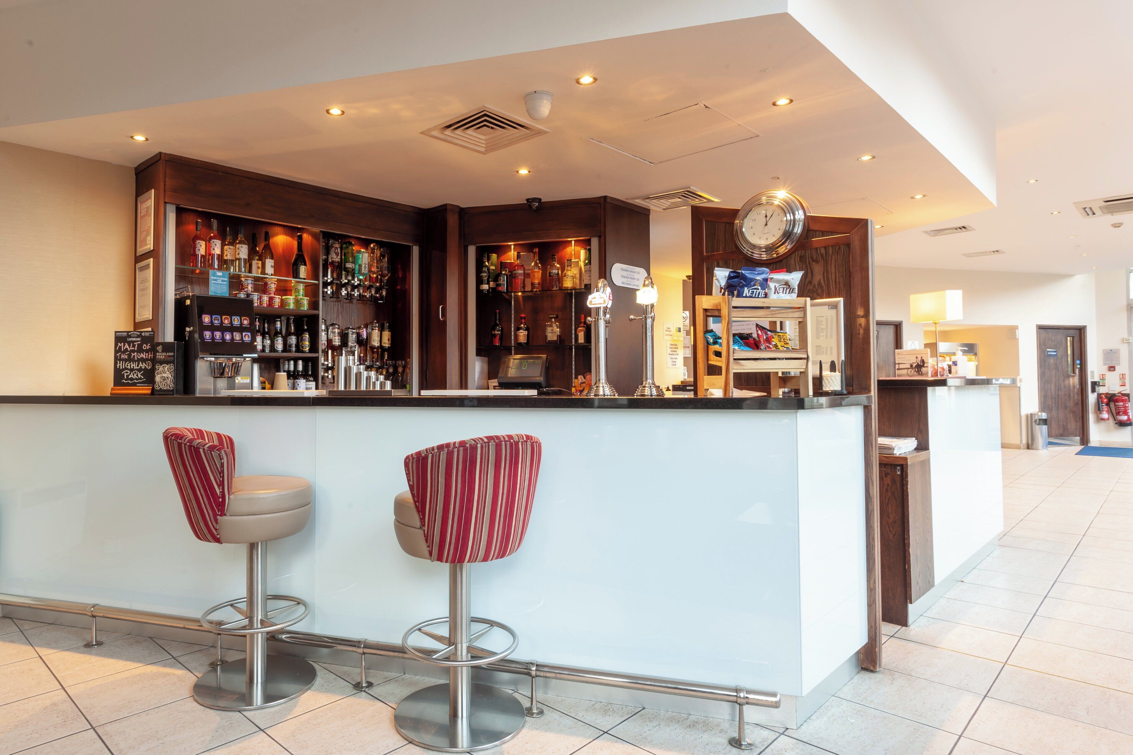 Uma área de bar com balcão, banquetas e diversas garrafas.