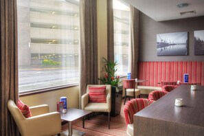 A hotel room with a large window, a seating area with striped chairs, a small table, and a decorative plant. - Holiday Inn Express Glasgow City Theatreland by IHG (Glasgow)
