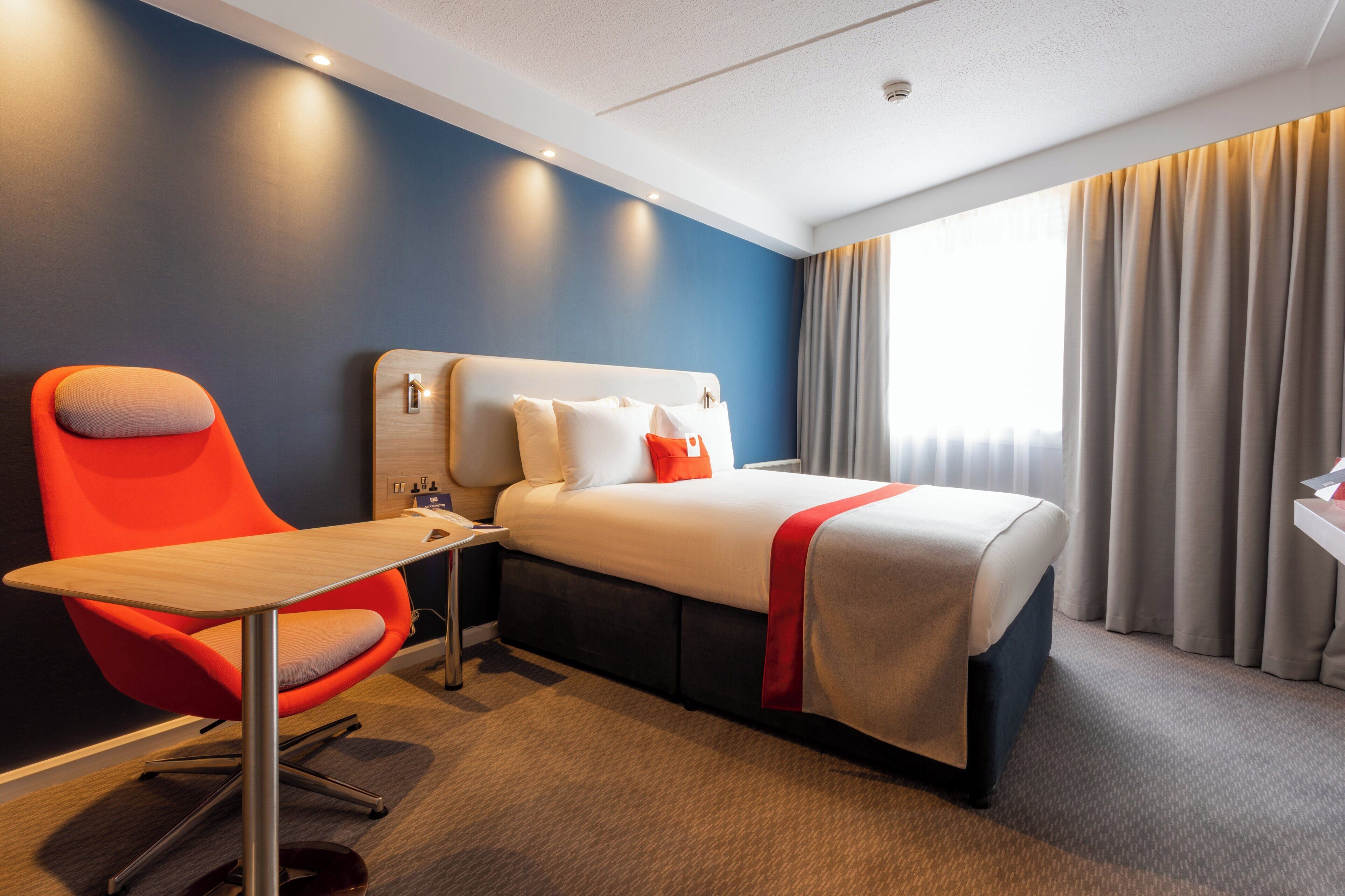 A hotel room with a bed, a desk, and a chair.