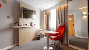 A modern hotel room with a wooden desk, a red chair, a flat-screen TV, and a large window with curtains. - Holiday Inn Express Glasgow City Theatreland by IHG (Glasgow)