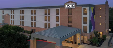 A hotel with a covered parking area, a brick facade, and a sign indicating it is a Hilton hotel.