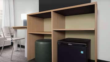 Une chambre d’hôtel équipée d’un bureau, d’une chaise et d’un réfrigérateur noir.