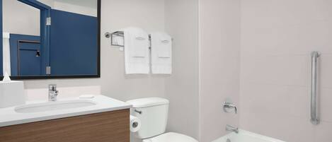 A modern bathroom with a white sink, toilet, and bathtub. There are two white towels hanging on a rack.