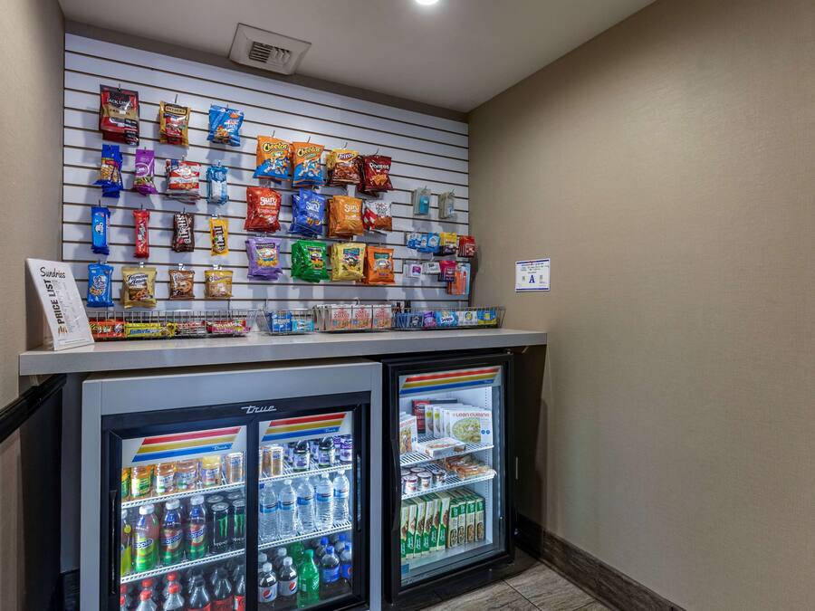Un mur dédié à la présentation d’en-cas, avec divers produits emballés, et un présentoir réfrigéré contenant des boissons et des produits en boîte.