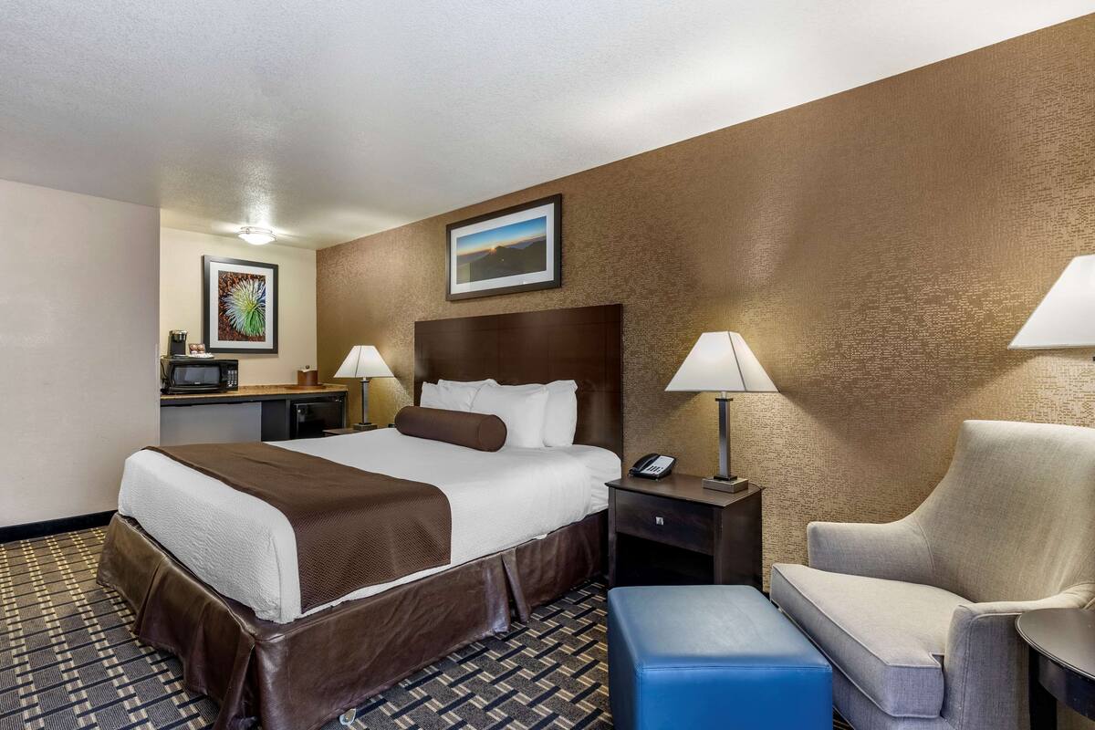 Ein Hotelzimmer mit einem großen Bett, einem Schreibtisch, einem Sessel und einem kleinen Tisch.