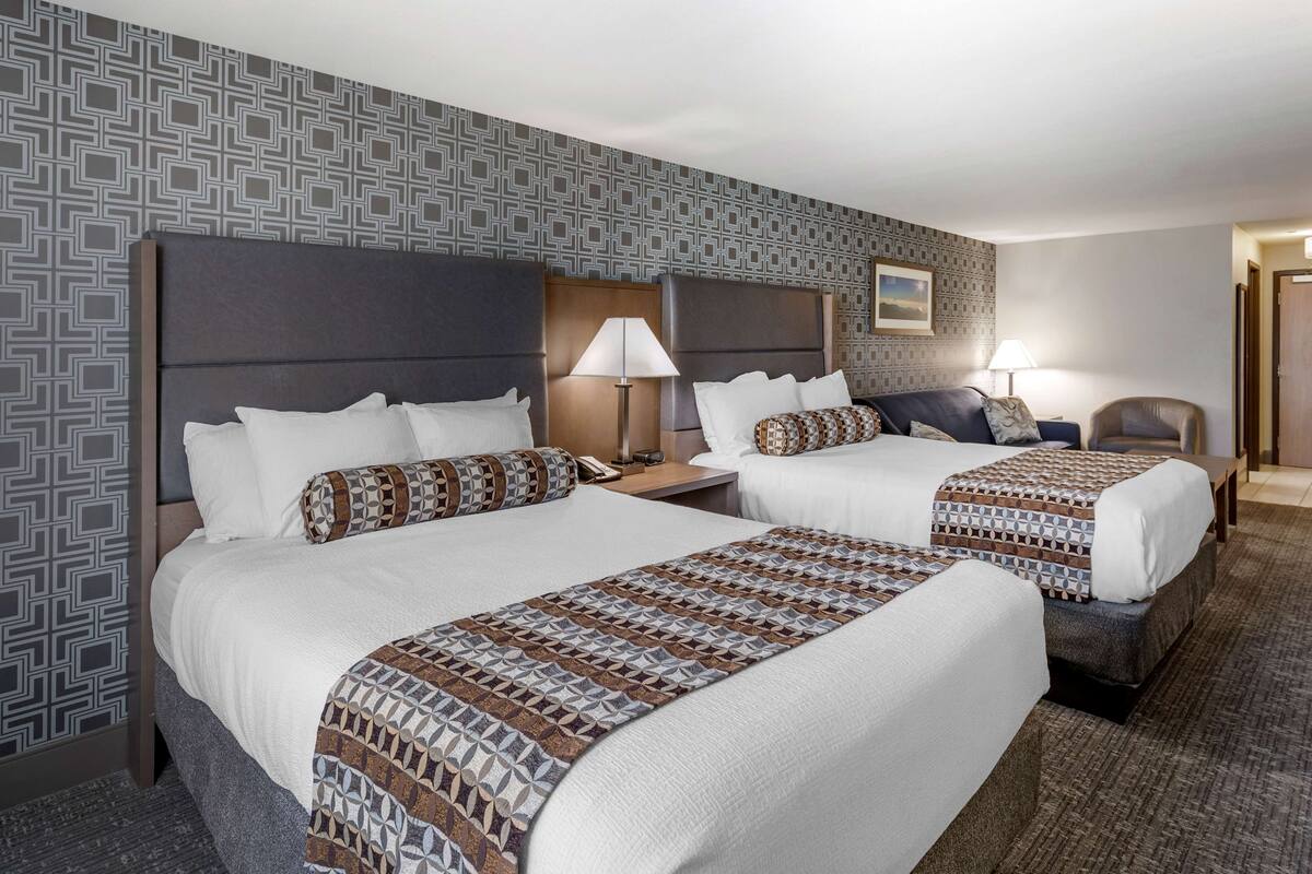 Ein Hotelzimmer mit zwei Betten, dekorativer Wandgestaltung und Teppichboden.