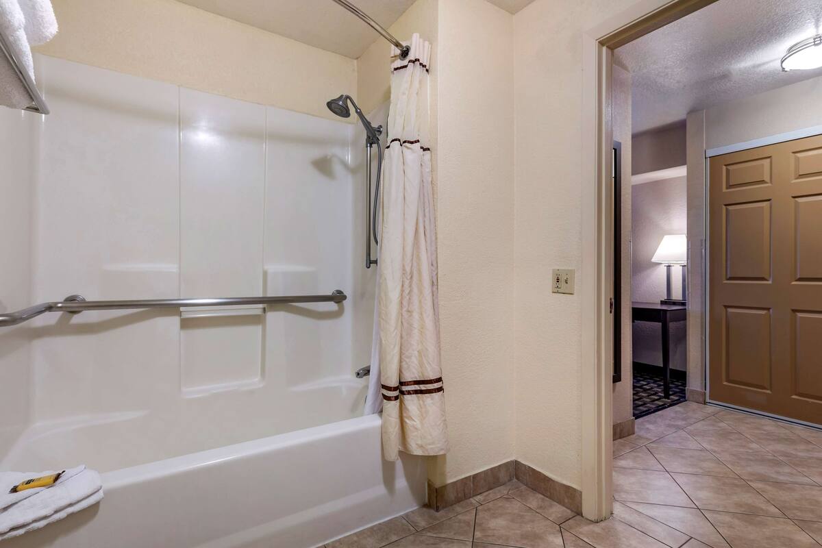 Ein Badezimmer mit einer weißen Badewanne, einer Dusche mit Duschbrause und einem Handtuchhalter mit Handtuch.