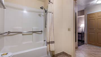 Un baño con una bañera blanca, una ducha con cabezal de ducha manual y un perchero con una toalla.