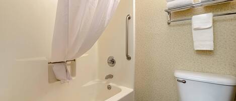 A bathroom with a bathtub, shower, toilet, and a towel rack with towels.